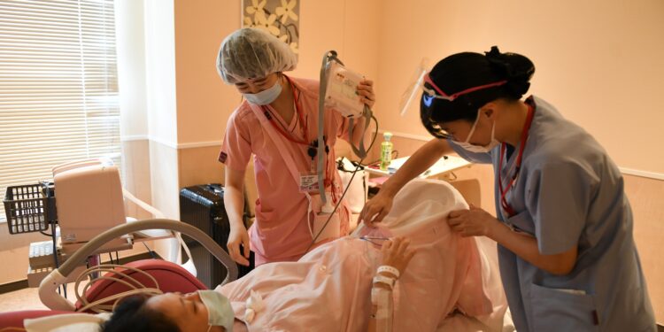A midwife Hotaru Tsuchida, left and Yuka Yamamoto a midwifery student of a university with a pregnant patient just before giving birth at Aiiku Hospital in Tokyo, Japan.